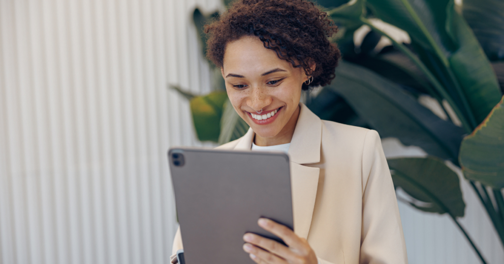 Mulher sorrindo enquanto utiliza um tablet, representando a facilidade e eficiência da automação financeira para a gestão empresarial.